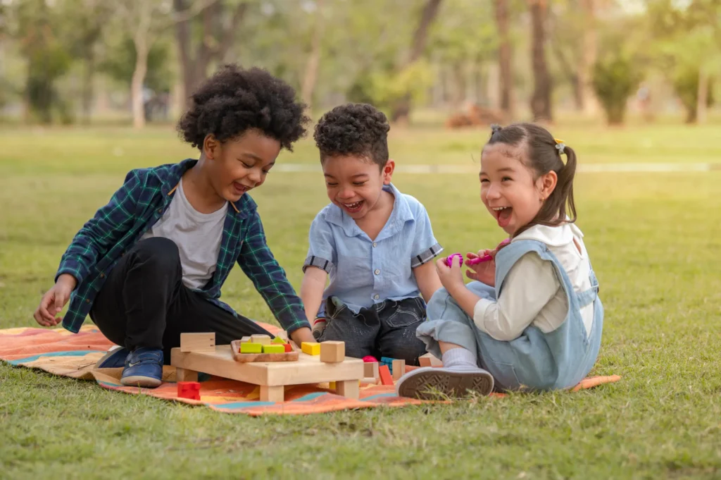 Happy kids playing with blocks outdoors, representing Neuro-Spark’s joyful learning